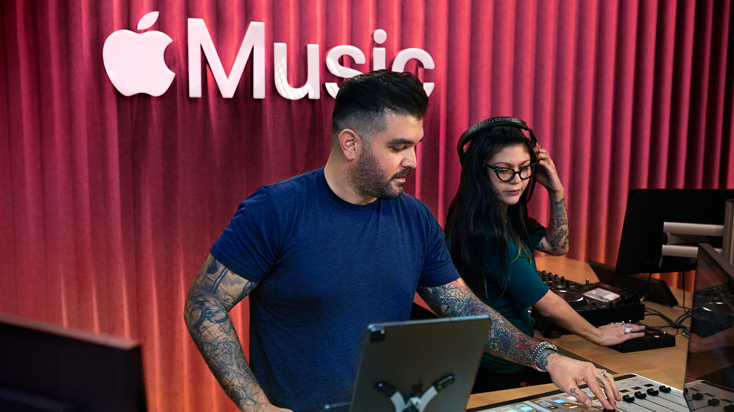 두 명의 Apple 동료가 Apple Music 스튜디오에서 사운드 믹싱 보드를 사용하고 있음.