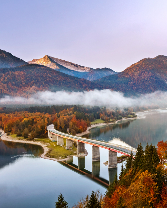 Un ponte su un lago con delle montagne sullo sfondo.