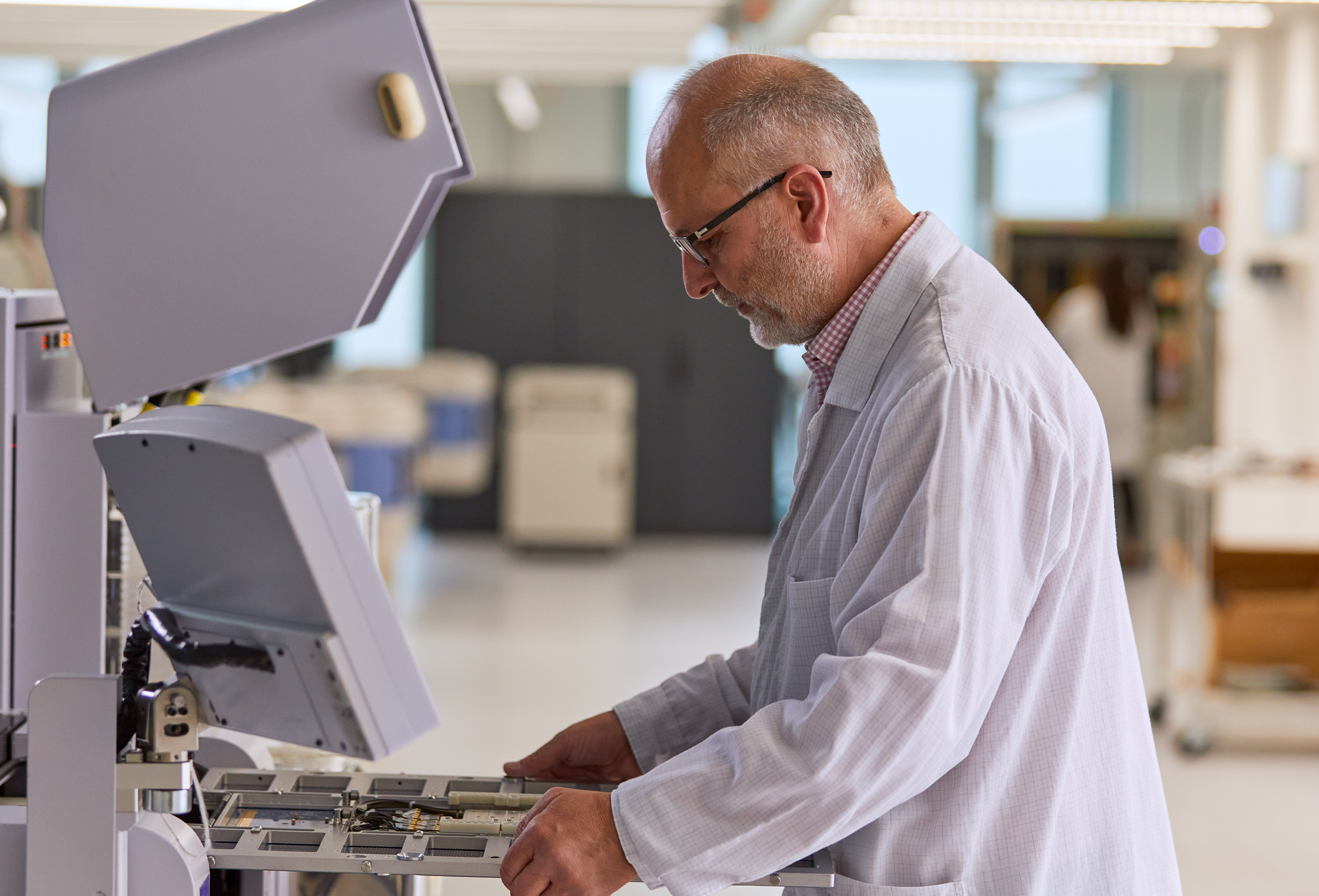 Un dipendente Apple che indossa un camice bianco da laboratorio e lavora su apparecchiature di ingegneria. 