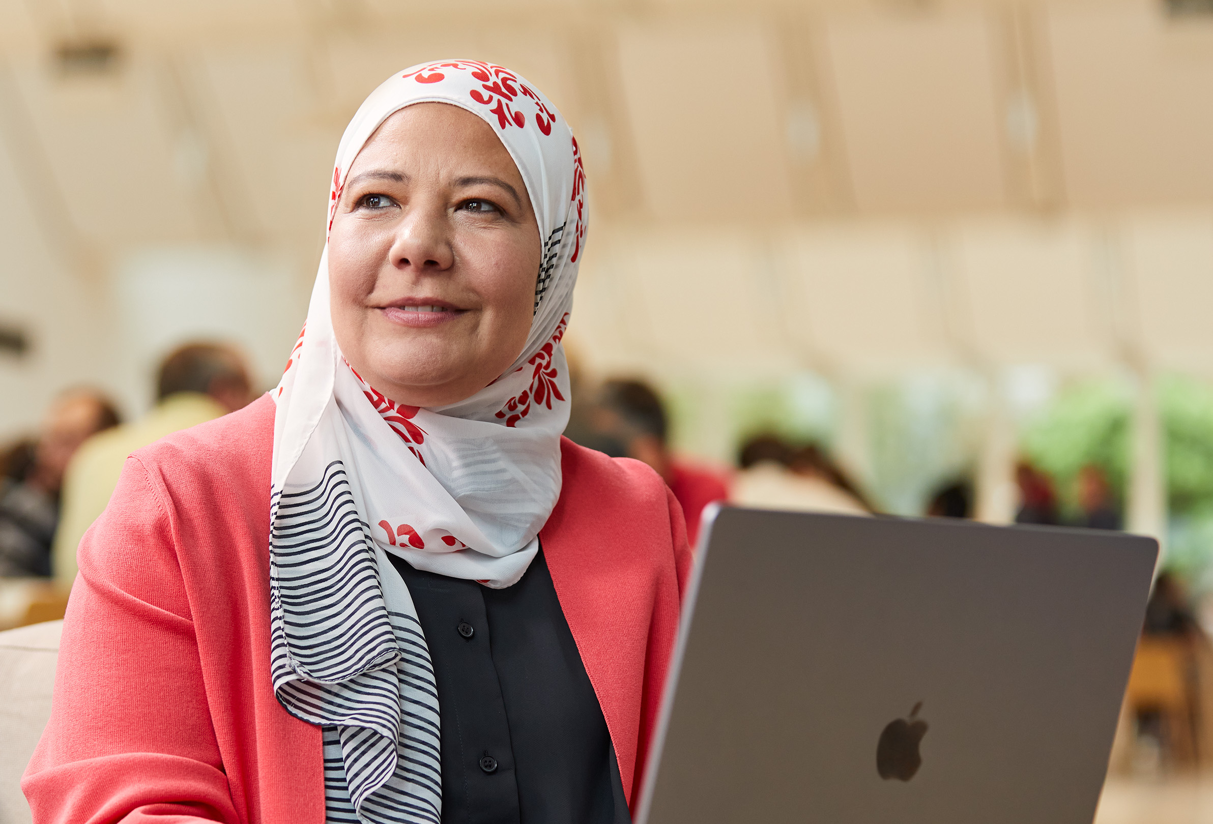 Una dipendente Apple seduta che guarda verso sinistra e lavora su un MacBook.