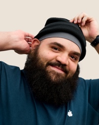 Un dipendente Apple Retail sorridente con una barba folta e un berretto nero.