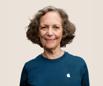 Una dipendente Apple Retail sorridente con i capelli mossi grigio scuro.