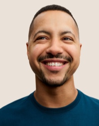 Un dipendente Apple Retail sorridente con i capelli corti scuri e la barba.