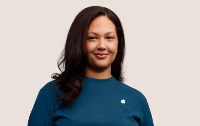 Una dipendente Apple Retail sorridente con i capelli lunghi scuri.