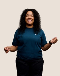 Una dipendente Apple Retail sorridente con i capelli lunghi, ricci e scuri.