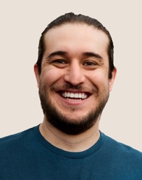 Un dipendente Apple Retail sorridente con i capelli scuri e la barba.