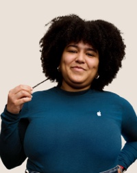 Una dipendente Apple Retail sorridente con i capelli lunghi, ricci e scuri.