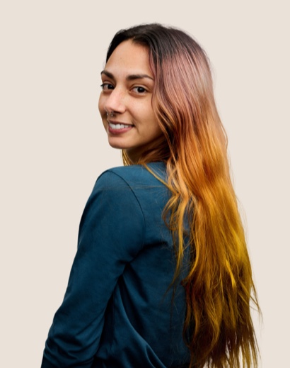 Una dipendente Apple Retail sorridente con i capelli lunghi castani che si volta indietro e guarda verso l’obiettivo.