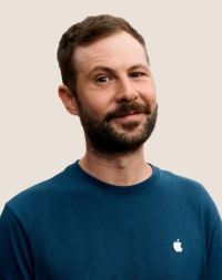 Un dipendente Apple Retail sorridente con i capelli scuri e la barba.