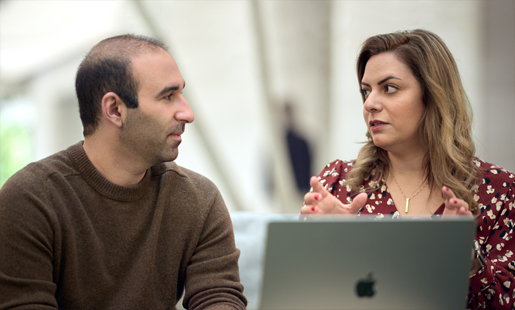 Desireh, sentada em frente a um MacBook, conversa com um colega.