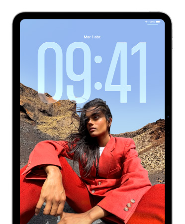 Un iPad muestra la pantalla bloqueada con grandes números de la hora que aparecen detrás de la foto de una persona sentada