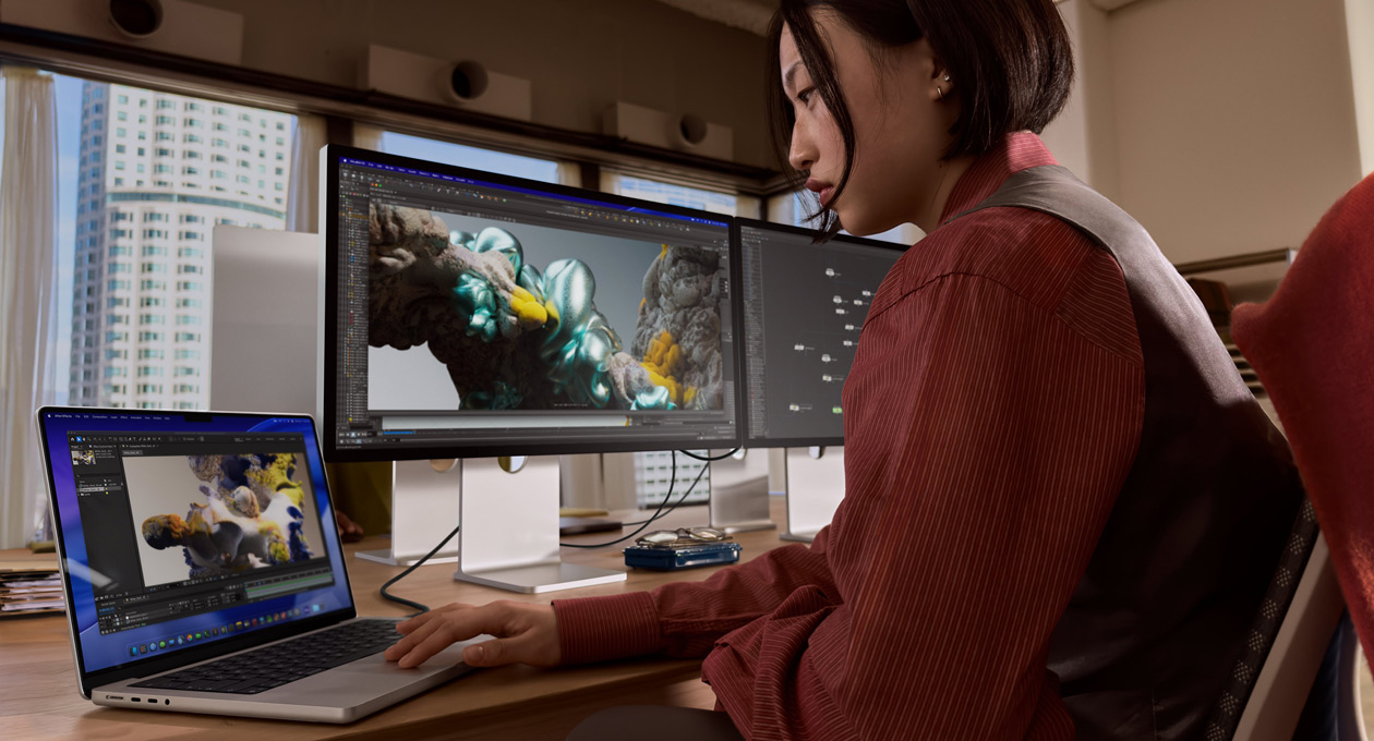 En person sidder ved en kontorplads og arbejder på en bærbar MacBook, der er forbundet til Studio Display XDR via en Thunderbolt 5-port