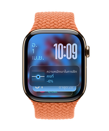 Apple Watch สีโรสโกลด์พร้อมสายแบบถักสีส้มแทนเจอรีน, หน้าปัดแสดงวันที่ที่ด้านซ้ายบน, เวลาแสดงด้วยตัวเลขซ้อนกันที่ด้านขวาบน, วิดเจ็ตความหนักเบาในการฝึกที่ด้านล่าง, ทั้งหมดนี้อยู่ใน Liquid Glass ที่โปร่งแสง