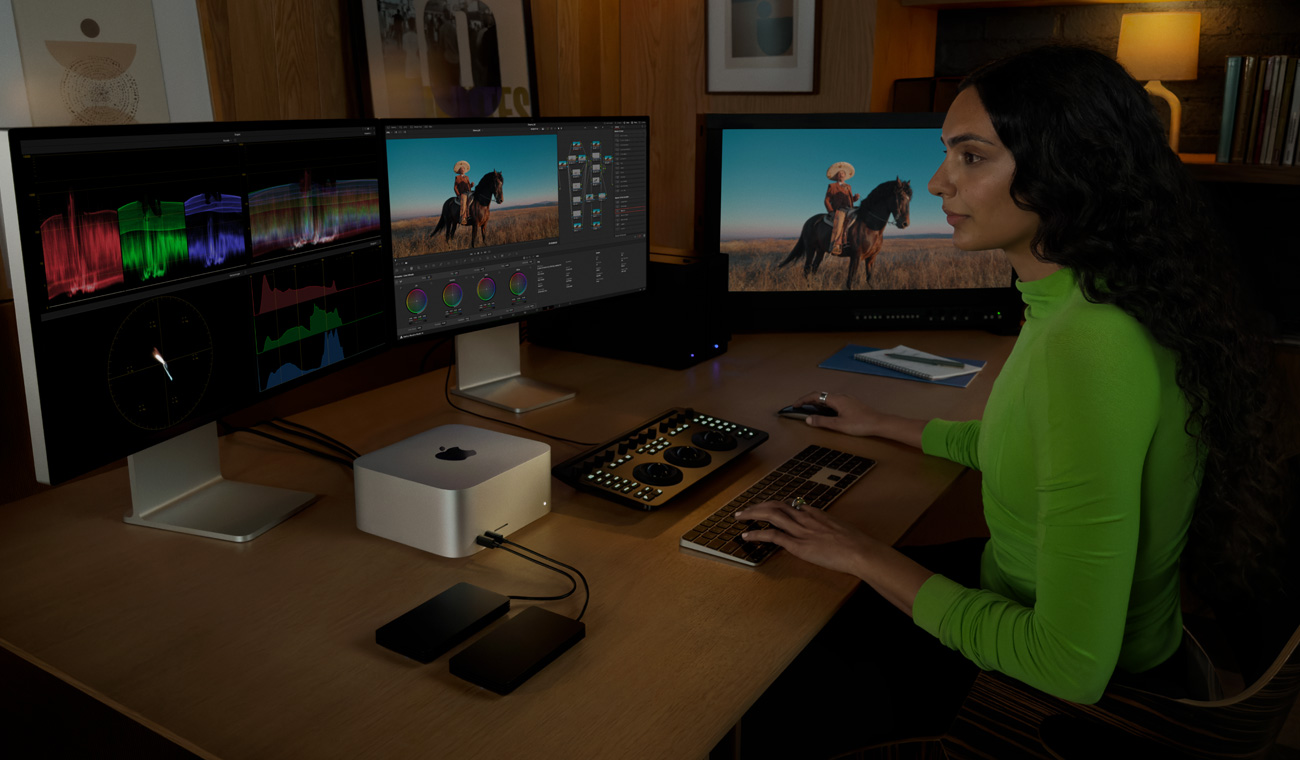 Een professional bewerkt bestanden op een Mac Studio met drie displays