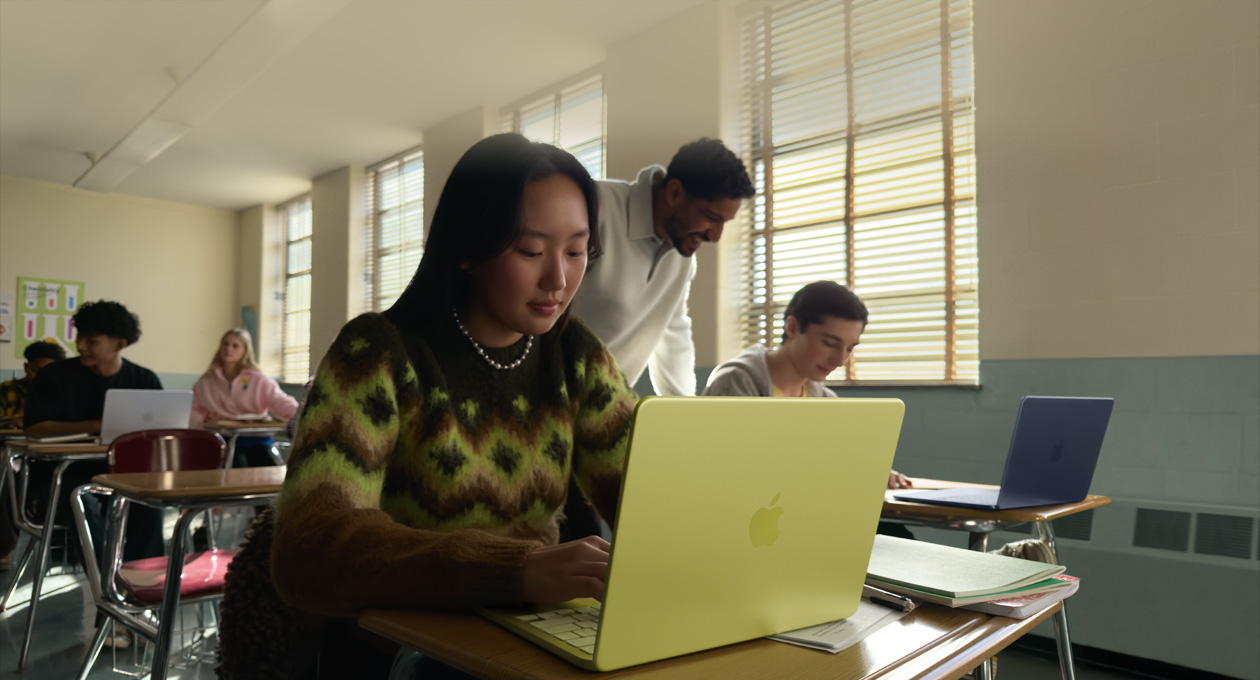 Eine Schülerin verwendet ein MacBook Neo in der Farbe Zitrus, das nicht am Strom angeschlossen ist, in einem Klassenzimmer