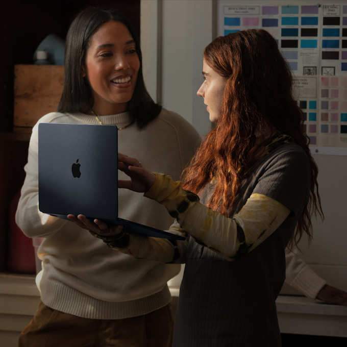 Nauczycielka rozmawiająca z uczennicą trzymającą MacBooka